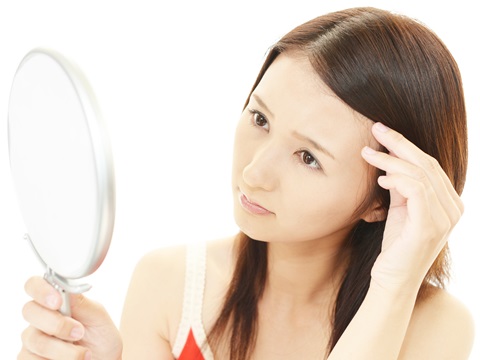顔のシミを気にする女性