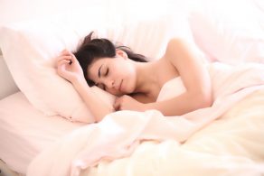 シーツにくるまって眠る裸の女性
