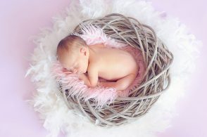 鳥の巣風バスケットの中で眠る赤ちゃん