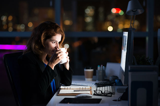 暗いオフィスで深夜残業をする女性