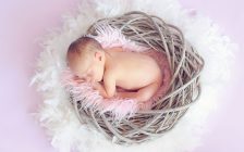 鳥の巣風バスケットの中で眠る赤ちゃん