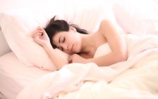 シーツにくるまって眠る裸の女性